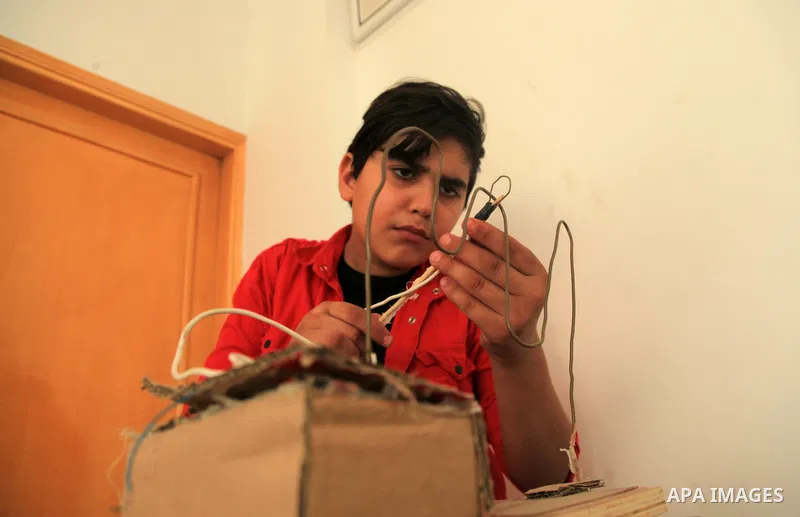 Palestinian inventor Mohammad Al-Hallaq,13, displays his small inventions at his home in Khan Yunis, in the southern Gaza Strip, on October 23, 2021. Al-Hallaq invented the robot for special needs and portable refrigerat...