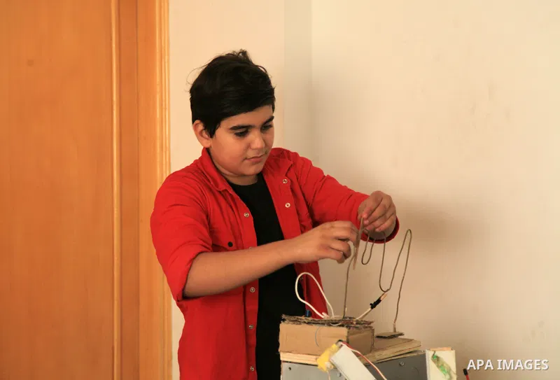 Palestinian inventor Mohammad Al-Hallaq,13, displays his small inventions at his home in Khan Yunis, in the southern Gaza Strip, on October 23, 2021. Al-Hallaq invented the robot for special needs and portable refrigerat...