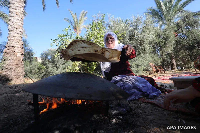 Palestinian women wear traditional dresses, as they pick olives during the harvest season, in Nuseirat camp in the central Gaza Strip, on 24 October 2021. Olive trees perform a crucial historical and cultural role in the...