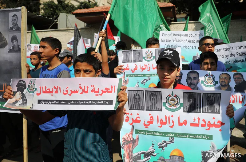 Palestinian children hold banners during a protest in solidarity with prisoners on hunger strike at Israeli jails, in front of Red Cross office in Gaza city on October 25, 2021. Photo by Mahmoud Nasser