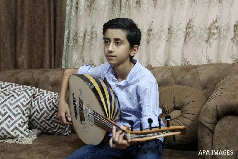 Palestinian boy Samih al Madhoun, 14, plays the oud and sings at his home, in Gaza city on October 26, 2021. al-Madhoun said that the passion for singing and composing is a talent that I worked a lot on developing and br...