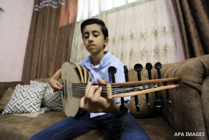 Palestinian boy Samih al Madhoun, 14, plays the oud and sings at his home, in Gaza city on October 26, 2021. al-Madhoun said that the passion for singing and composing is a talent that I worked a lot on developing and br...