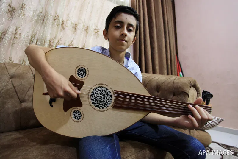 Palestinian boy Samih al Madhoun, 14, plays the oud and sings at his home, in Gaza city on October 26, 2021. al-Madhoun said that the passion for singing and composing is a talent that I worked a lot on developing and br...