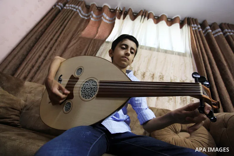 Palestinian boy Samih al Madhoun, 14, plays the oud and sings at his home, in Gaza city on October 26, 2021. al-Madhoun said that the passion for singing and composing is a talent that I worked a lot on developing and br...