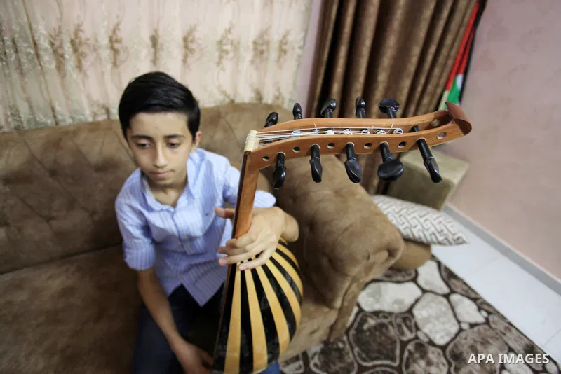 Palestinian boy Samih al Madhoun, 14, plays the oud and sings at his home, in Gaza city on October 26, 2021. al-Madhoun said that the passion for singing and composing is a talent that I worked a lot on developing and br...