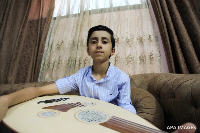 Palestinian boy Samih al Madhoun, 14, plays the oud and sings at his home, in Gaza city on October 26, 2021. al-Madhoun said that the passion for singing and composing is a talent that I worked a lot on developing and br...
