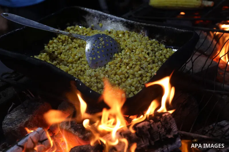 Palestinian men grill corn on the cob at a stall on Gaza City's seaside and sell it to customers, on October 26, 2021. Photo by Magdy Fathi