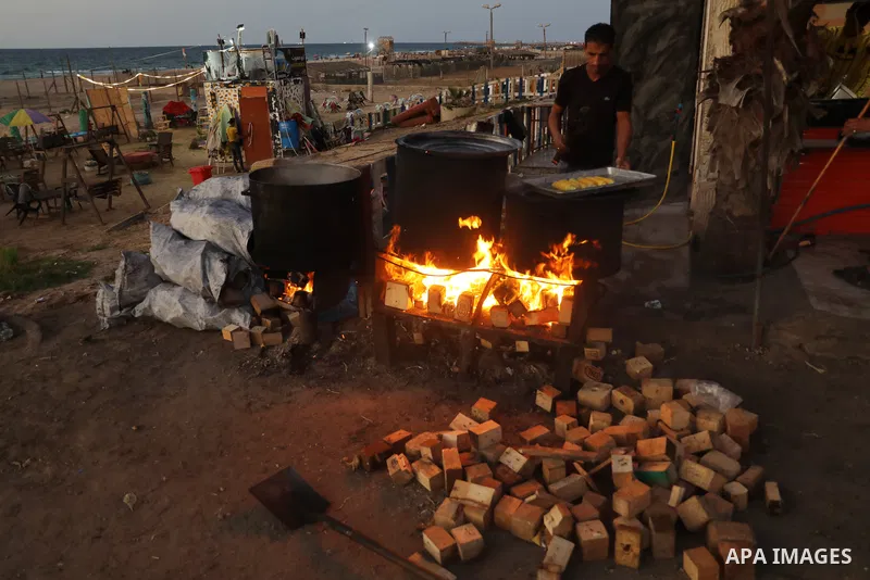 Palestinian men grill corn on the cob at a stall on Gaza City's seaside and sell it to customers, on October 26, 2021. Photo by Magdy Fathi