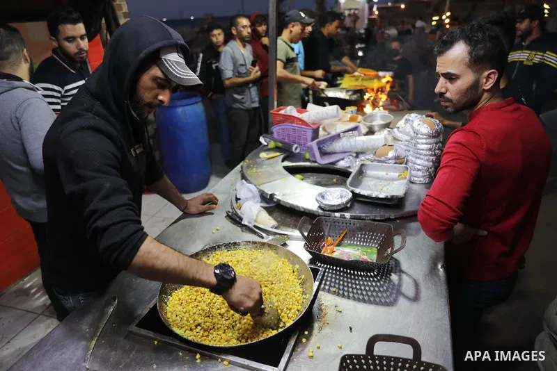 Palestinian men grill corn on the cob at a stall on Gaza City's seaside and sell it to customers, on October 26, 2021. Photo by Magdy Fathi