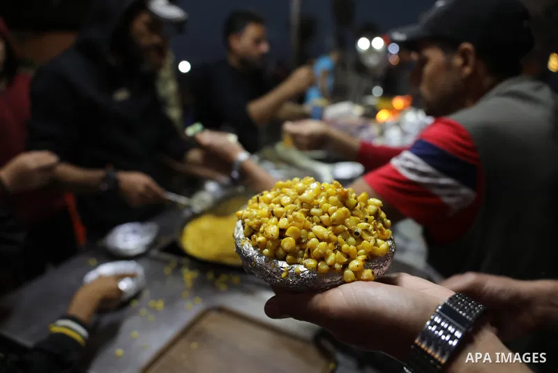Palestinian men grill corn on the cob at a stall on Gaza City's seaside and sell it to customers, on October 26, 2021. Photo by Magdy Fathi