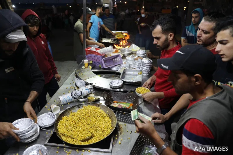 Palestinian men grill corn on the cob at a stall on Gaza City's seaside and sell it to customers, on October 26, 2021. Photo by Magdy Fathi