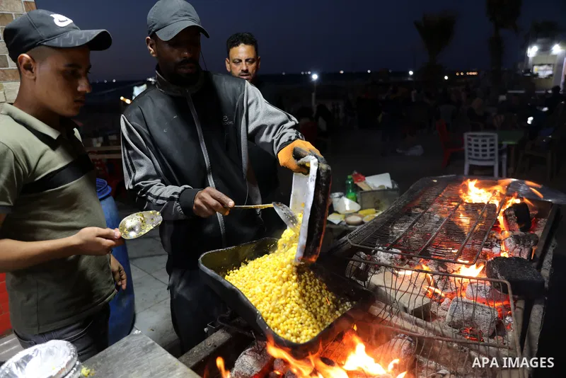 Palestinian men grill corn on the cob at a stall on Gaza City's seaside and sell it to customers, on October 26, 2021. Photo by Magdy Fathi