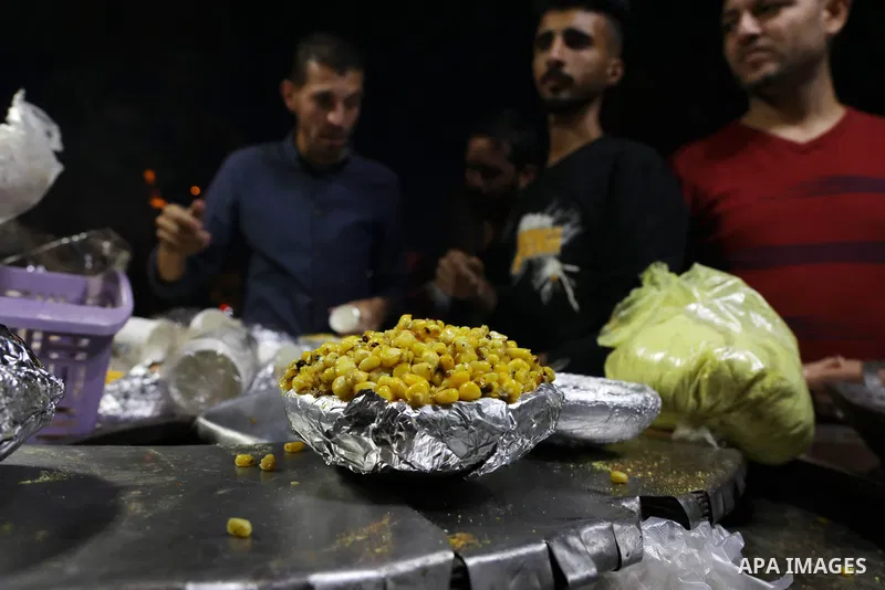 Palestinian men grill corn on the cob at a stall on Gaza City's seaside and sell it to customers, on October 26, 2021. Photo by Magdy Fathi