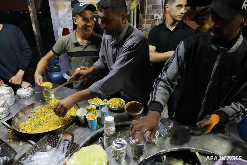 Palestinian men grill corn on the cob at a stall on Gaza City's seaside and sell it to customers, on October 26, 2021. Photo by Magdy Fathi
