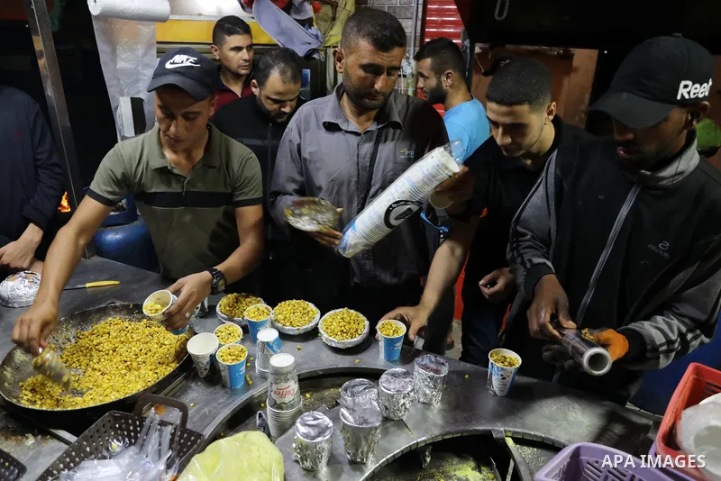 Palestinian men grill corn on the cob at a stall on Gaza City's seaside and sell it to customers, on October 26, 2021. Photo by Magdy Fathi