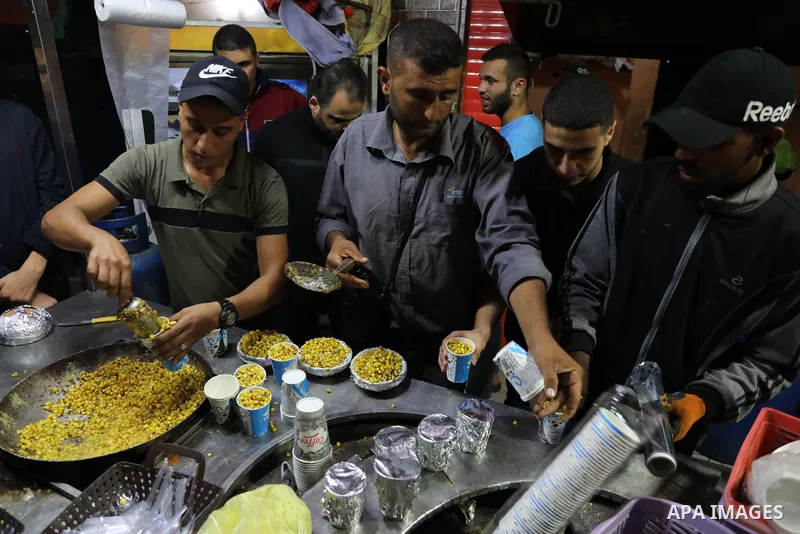 Palestinian men grill corn on the cob at a stall on Gaza City's seaside and sell it to customers, on October 26, 2021. Photo by Magdy Fathi