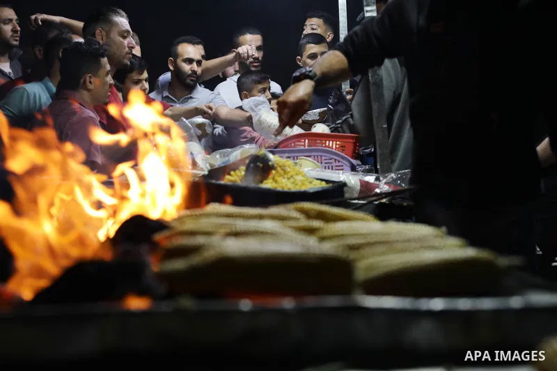 Palestinian men grill corn on the cob at a stall on Gaza City's seaside and sell it to customers, on October 26, 2021. Photo by Magdy Fathi