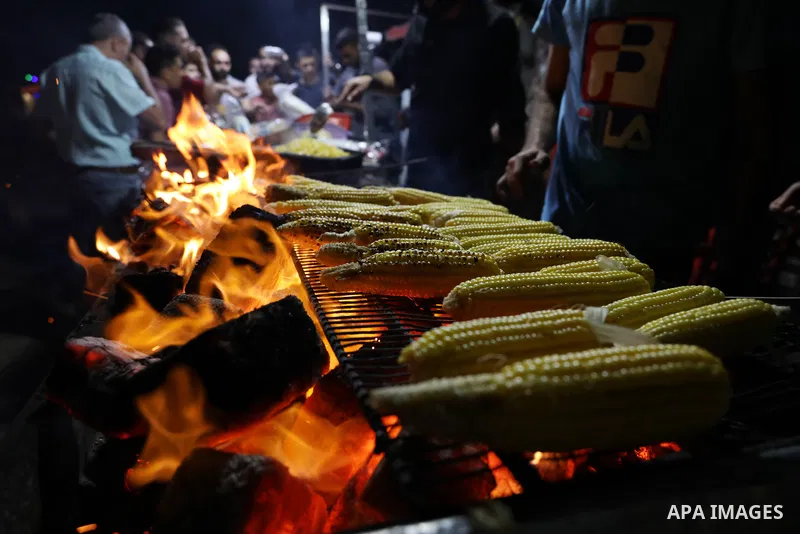 Palestinian men grill corn on the cob at a stall on Gaza City's seaside and sell it to customers, on October 26, 2021. Photo by Magdy Fathi