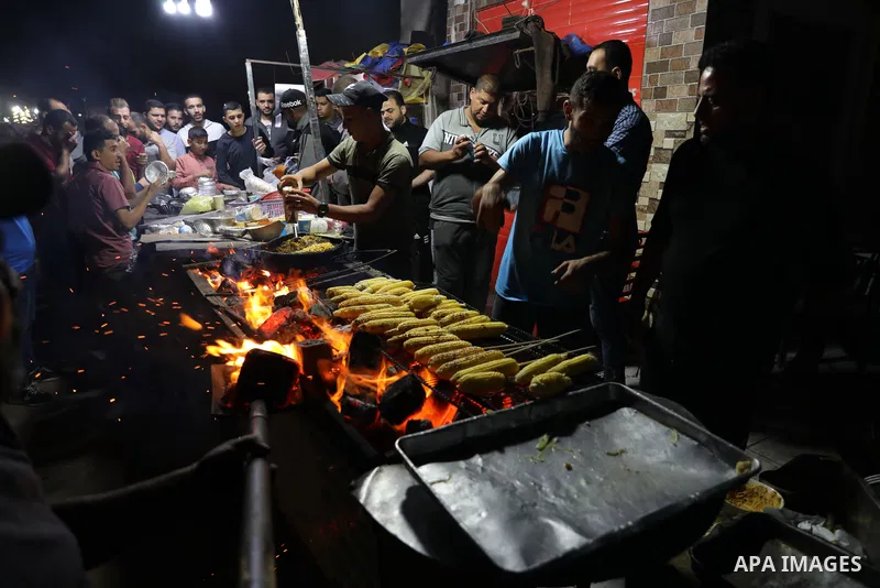 Palestinian men grill corn on the cob at a stall on Gaza City's seaside and sell it to customers, on October 26, 2021. Photo by Magdy Fathi