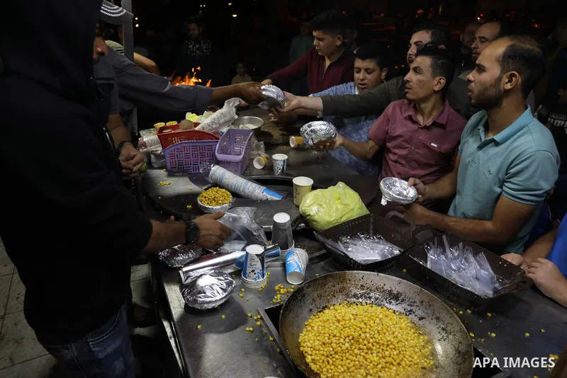 Palestinian men grill corn on the cob at a stall on Gaza City's seaside and sell it to customers, on October 26, 2021. Photo by Magdy Fathi