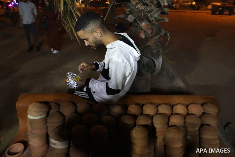 Palestinian men grill corn on the cob at a stall on Gaza City's seaside and sell it to customers, on October 26, 2021. Photo by Magdy Fathi