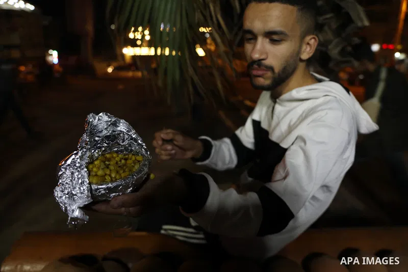 Palestinian men grill corn on the cob at a stall on Gaza City's seaside and sell it to customers, on October 26, 2021. Photo by Magdy Fathi