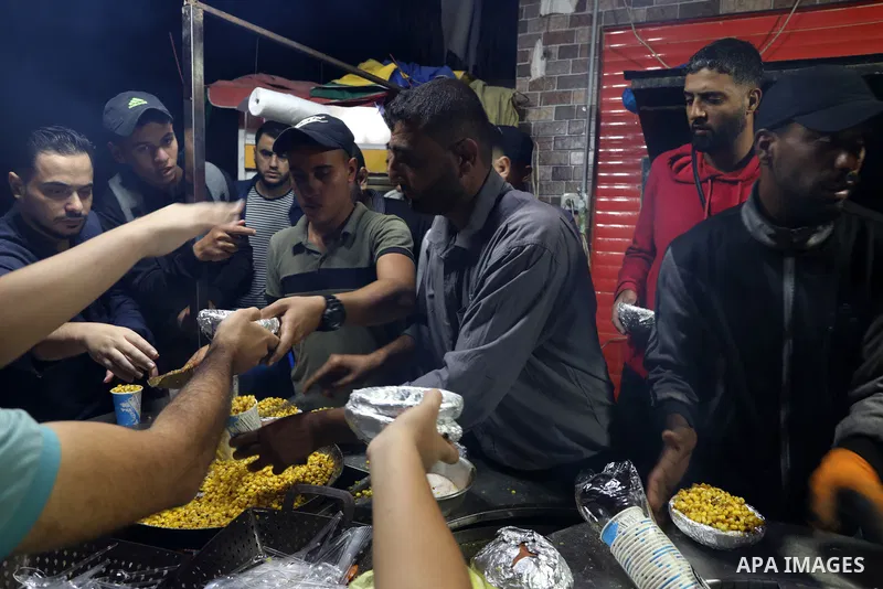 Palestinian men grill corn on the cob at a stall on Gaza City's seaside and sell it to customers, on October 26, 2021. Photo by Magdy Fathi