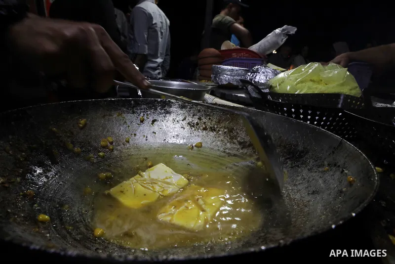 Palestinian men grill corn on the cob at a stall on Gaza City's seaside and sell it to customers, on October 26, 2021. Photo by Magdy Fathi
