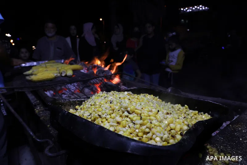 Palestinian men grill corn on the cob at a stall on Gaza City's seaside and sell it to customers, on October 26, 2021. Photo by Magdy Fathi