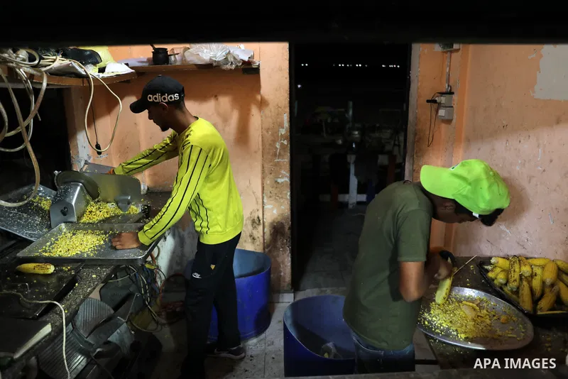 Palestinian men grill corn on the cob at a stall on Gaza City's seaside and sell it to customers, on October 26, 2021. Photo by Magdy Fathi