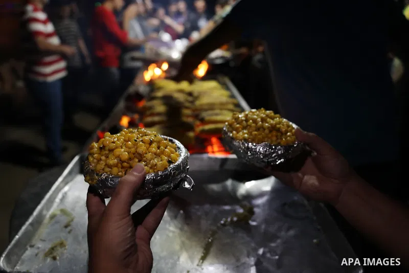 Palestinian men grill corn on the cob at a stall on Gaza City's seaside and sell it to customers, on October 26, 2021. Photo by Magdy Fathi