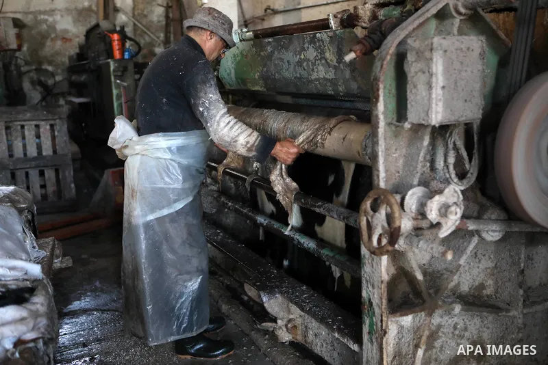 Palestinian workers paint leather and putting pieces out to dry as part of the finish process of leather tanning in a small factory to sell it to manufacture of shoes, in the West Bank city of Hebron on October 27, 2021....