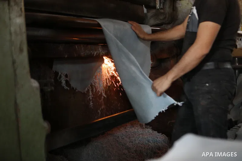 Palestinian workers paint leather and putting pieces out to dry as part of the finish process of leather tanning in a small factory to sell it to manufacture of shoes, in the West Bank city of Hebron on October 27, 2021....