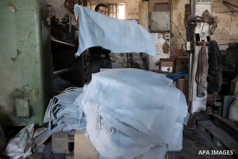 Palestinian workers paint leather and putting pieces out to dry as part of the finish process of leather tanning in a small factory to sell it to manufacture of shoes, in the West Bank city of Hebron on October 27, 2021....