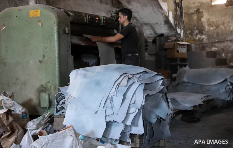 Palestinian workers paint leather and putting pieces out to dry as part of the finish process of leather tanning in a small factory to sell it to manufacture of shoes, in the West Bank city of Hebron on October 27, 2021....