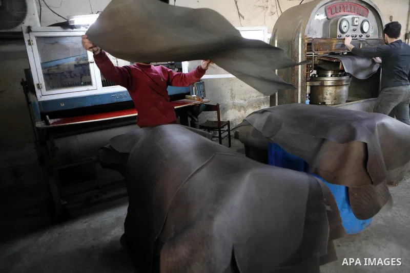 Palestinian workers paint leather and putting pieces out to dry as part of the finish process of leather tanning in a small factory to sell it to manufacture of shoes, in the West Bank city of Hebron on October 27, 2021....