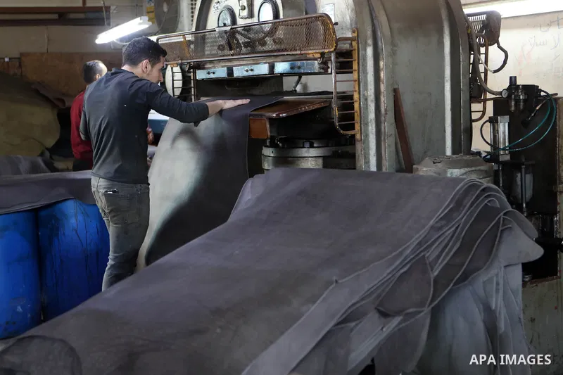 Palestinian workers paint leather and putting pieces out to dry as part of the finish process of leather tanning in a small factory to sell it to manufacture of shoes, in the West Bank city of Hebron on October 27, 2021....