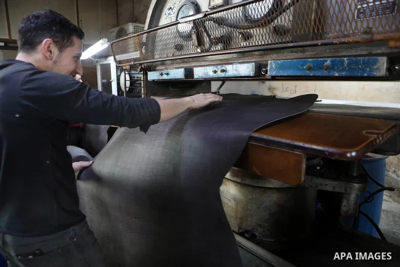 Palestinian workers paint leather and putting pieces out to dry as part of the finish process of leather tanning in a small factory to sell it to manufacture of shoes, in the West Bank city of Hebron on October 27, 2021....