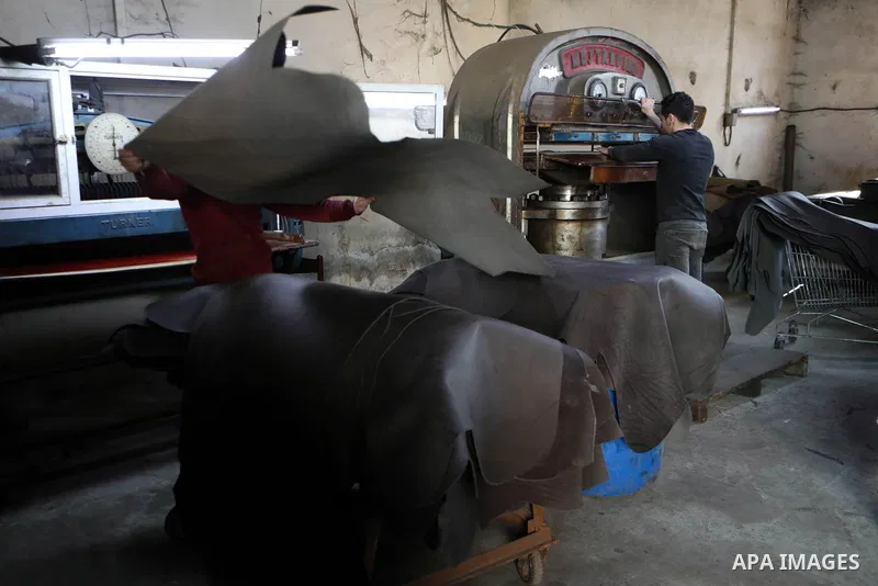 Palestinian workers paint leather and putting pieces out to dry as part of the finish process of leather tanning in a small factory to sell it to manufacture of shoes, in the West Bank city of Hebron on October 27, 2021....