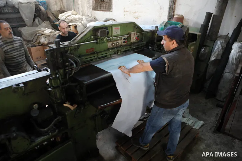 Palestinian workers paint leather and putting pieces out to dry as part of the finish process of leather tanning in a small factory to sell it to manufacture of shoes, in the West Bank city of Hebron on October 27, 2021....
