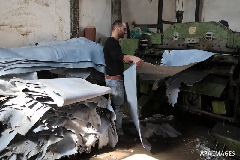 Palestinian workers paint leather and putting pieces out to dry as part of the finish process of leather tanning in a small factory to sell it to manufacture of shoes, in the West Bank city of Hebron on October 27, 2021....