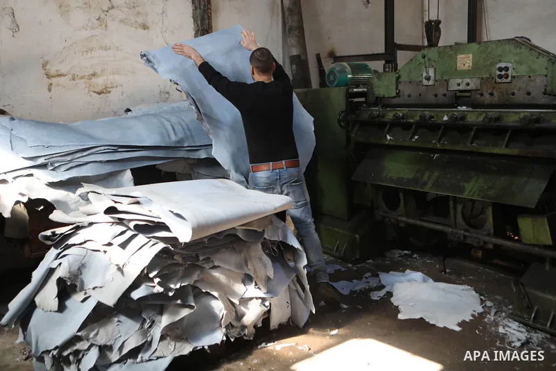 Palestinian workers paint leather and putting pieces out to dry as part of the finish process of leather tanning in a small factory to sell it to manufacture of shoes, in the West Bank city of Hebron on October 27, 2021....