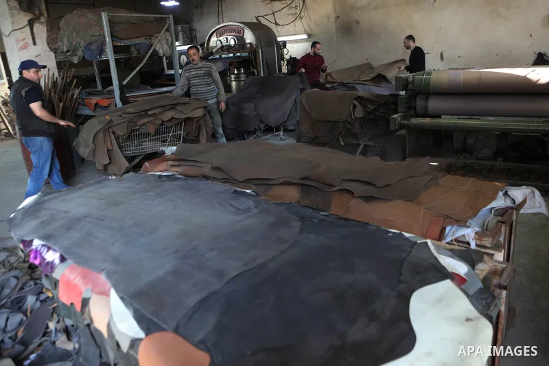 Palestinian workers paint leather and putting pieces out to dry as part of the finish process of leather tanning in a small factory to sell it to manufacture of shoes, in the West Bank city of Hebron on October 27, 2021....