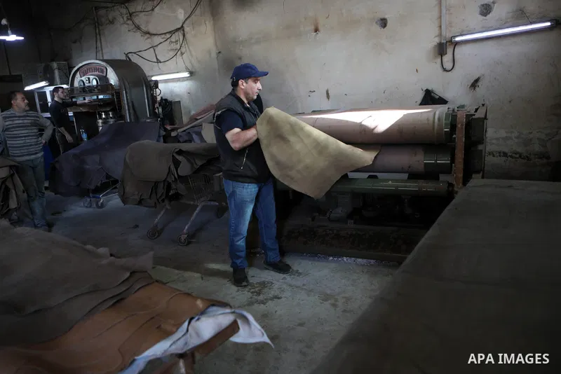 Palestinian workers paint leather and putting pieces out to dry as part of the finish process of leather tanning in a small factory to sell it to manufacture of shoes, in the West Bank city of Hebron on October 27, 2021....