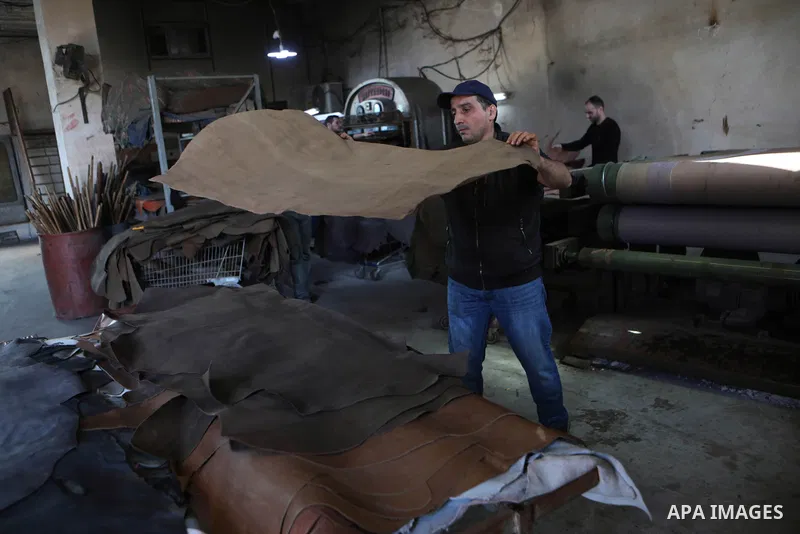 Palestinian workers paint leather and putting pieces out to dry as part of the finish process of leather tanning in a small factory to sell it to manufacture of shoes, in the West Bank city of Hebron on October 27, 2021....