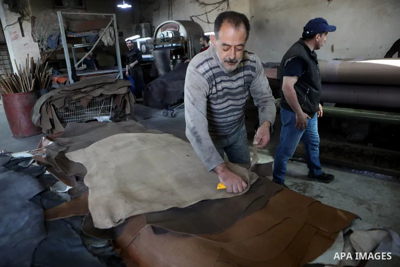 Palestinian workers paint leather and putting pieces out to dry as part of the finish process of leather tanning in a small factory to sell it to manufacture of shoes, in the West Bank city of Hebron on October 27, 2021....