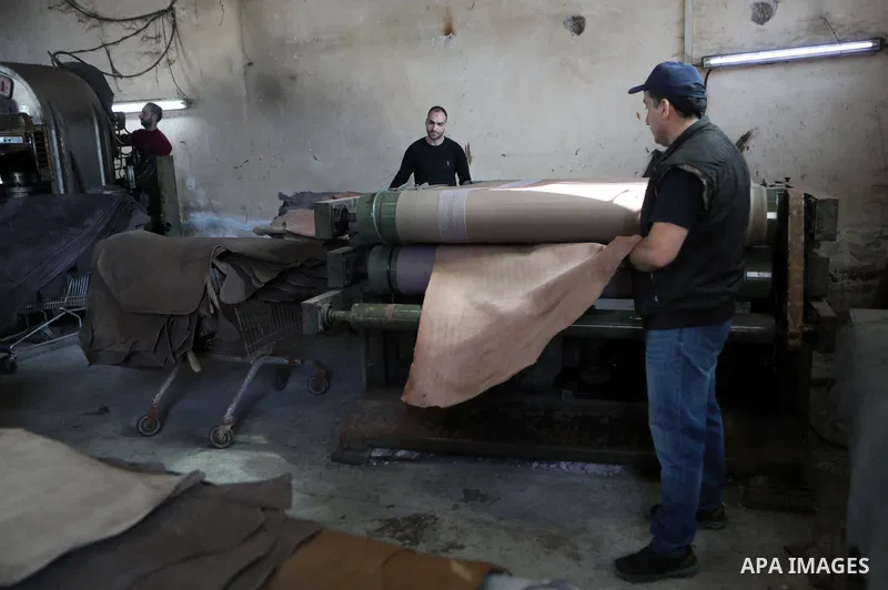 Palestinian workers paint leather and putting pieces out to dry as part of the finish process of leather tanning in a small factory to sell it to manufacture of shoes, in the West Bank city of Hebron on October 27, 2021....