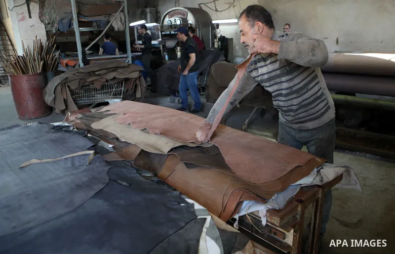 Palestinian workers paint leather and putting pieces out to dry as part of the finish process of leather tanning in a small factory to sell it to manufacture of shoes, in the West Bank city of Hebron on October 27, 2021....