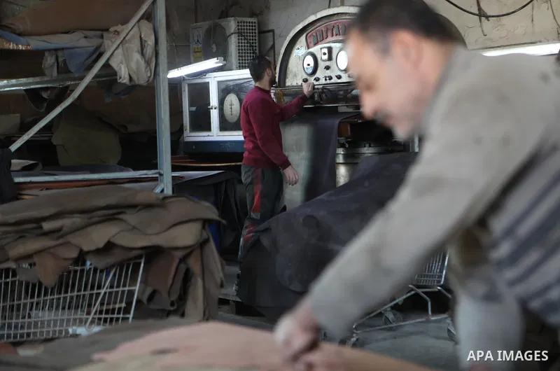 Palestinian workers paint leather and putting pieces out to dry as part of the finish process of leather tanning in a small factory to sell it to manufacture of shoes, in the West Bank city of Hebron on October 27, 2021....