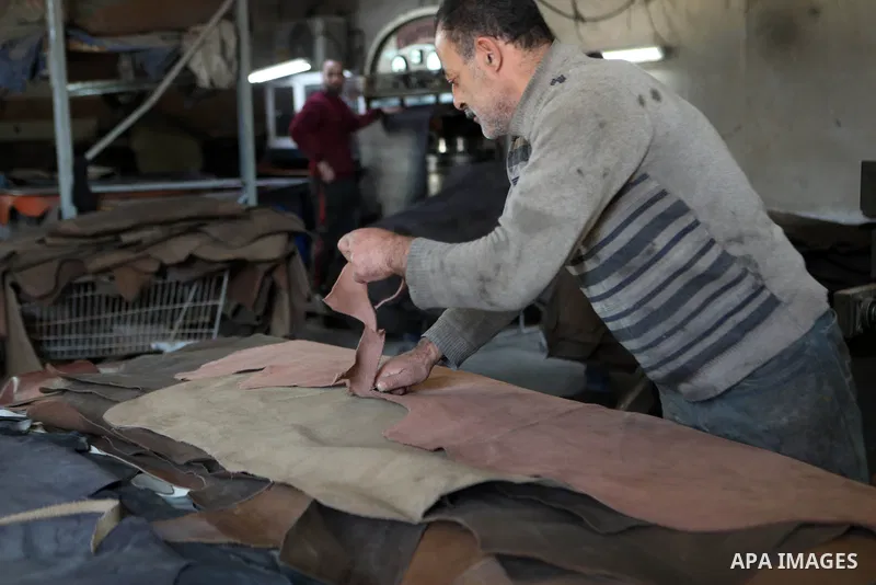 Palestinian workers paint leather and putting pieces out to dry as part of the finish process of leather tanning in a small factory to sell it to manufacture of shoes, in the West Bank city of Hebron on October 27, 2021....